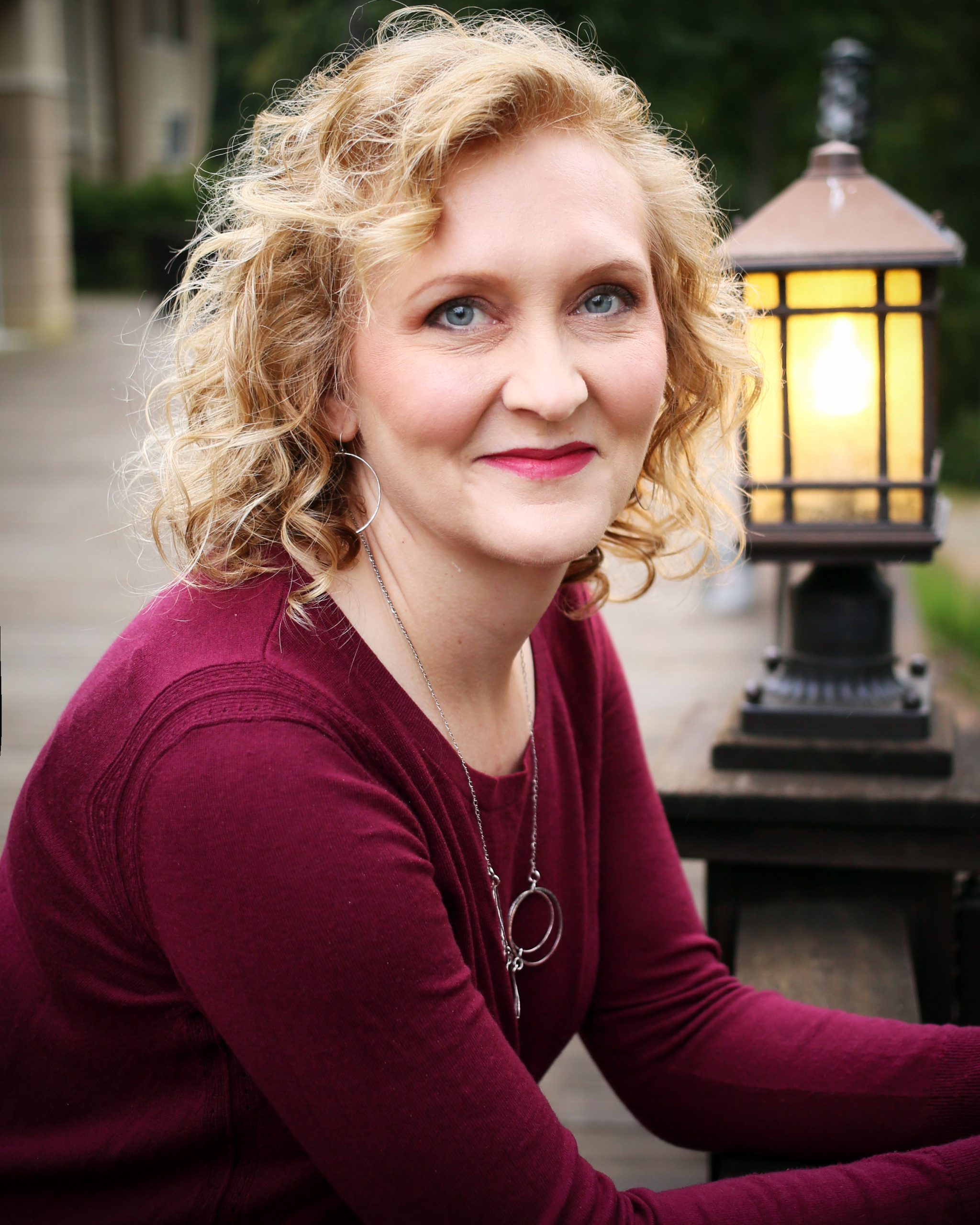 Michelle McCraw wearing a red sweater and leaning on a banister outdoors